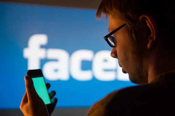 Facebook uygulaması smartphone kullanan adam