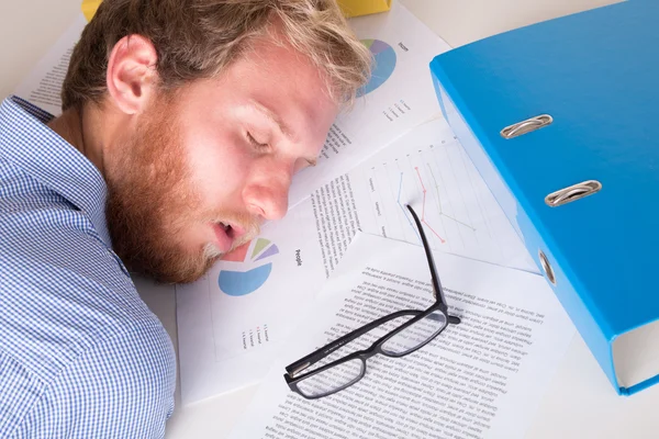 Young man sleeping on papers — Stock Photo, Image