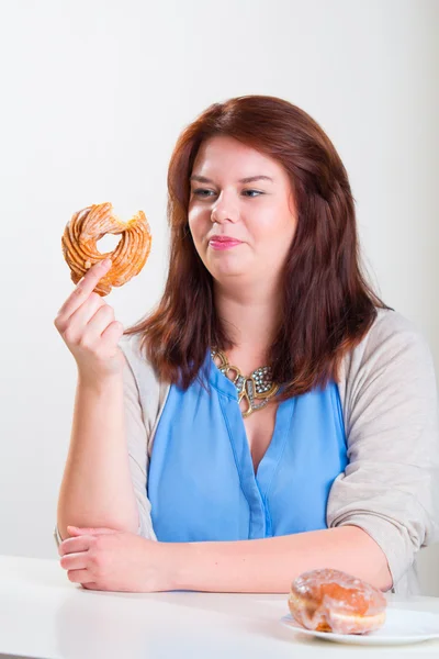 Knubbig kvinna äta donut — Stockfoto