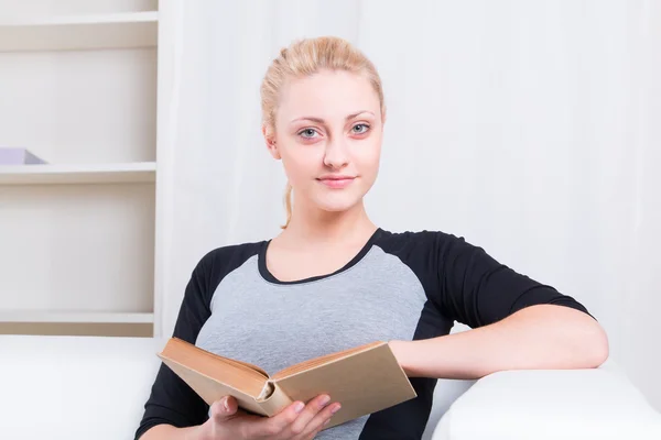Vacker kvinna läser bok på soffa — Stockfoto