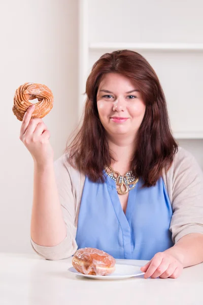 Knubbig kvinna anläggning donut — Stockfoto