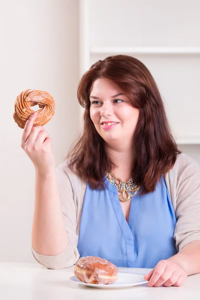 Толстая женщина ест пончики — стоковое фото