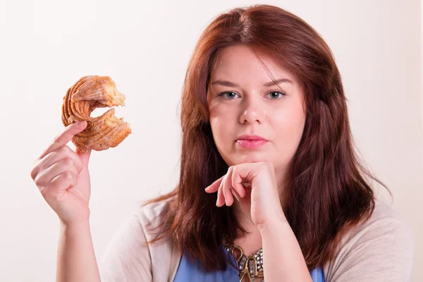 Knubbig kvinna äta donut — Stockfoto
