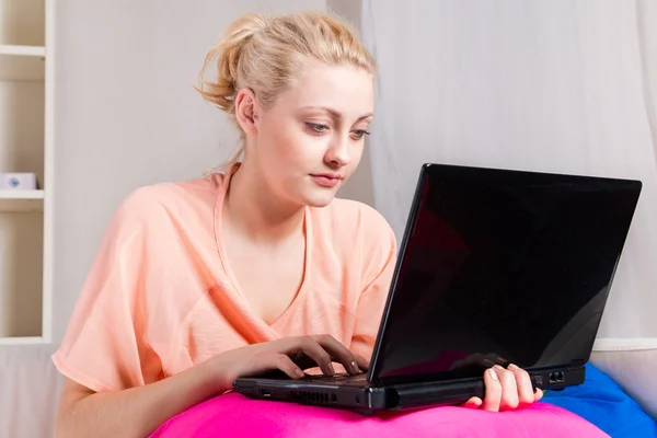 सुनहरे बालों वाली लड़की लैपटॉप के साथ सोफा पर बैठी — स्टॉक फ़ोटो, इमेज