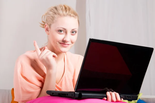 Blondine pige sidder på sofaen med laptop - Stock-foto