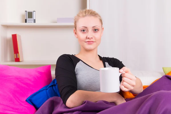 Femme sur canapé avec tasse de thé — Photo