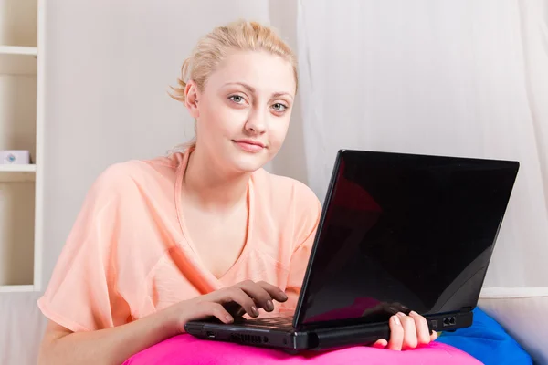 Menina loira sentada no sofá com laptop — Fotografia de Stock