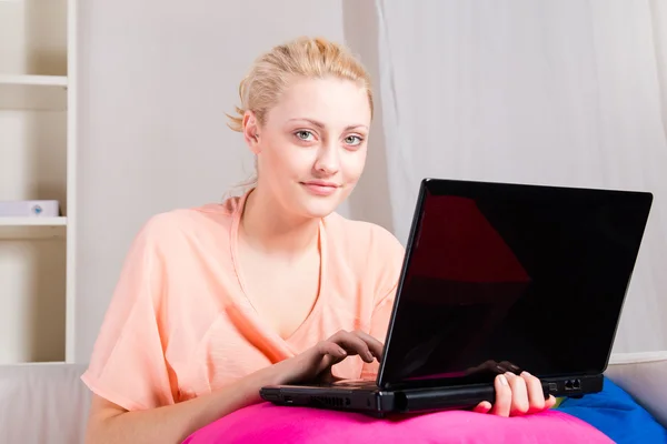 Menina loira sentada no sofá com laptop — Fotografia de Stock