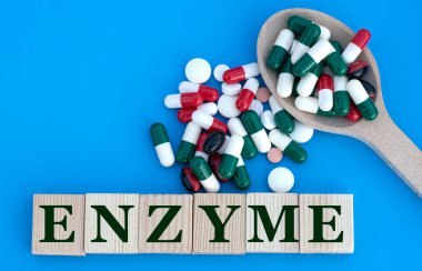 Mavi arka plandaki küplerle ilgili EnzyME kelimesi ve haplı bir kaşık. Tıbbi konsept