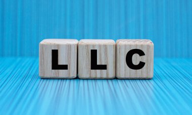 LLC (Sınırlı Sorumluluk Şirketi - güzel mavi arka planda tahta küplerle ilgili kelime. İş ve finans kavramı.