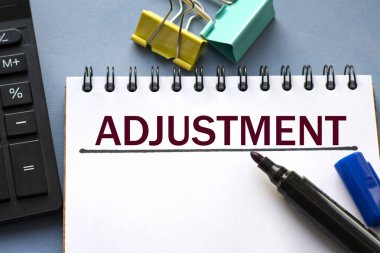 ADJUSTMENT kelimesi bir deftere işaretleyici, hesap makinesi, kıskaç ve kaktüs ile yazılır. İş konsepti