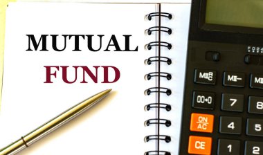 Hesap makinesinin arka planına karşı dizüstü bilgisayarda MUTUAL FUND kelime. İş ve finans kavramı.