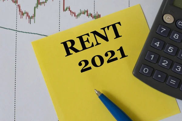 RENT 2021 word on yellow sheet on table with pen, calculator and graph. Business and finance concept.