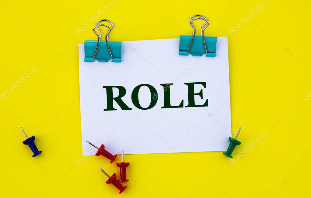 ROLE - Word on white paper with clips on yellow background with buttons and pencil. Education concept