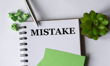 HATA - beyaz arka planda bir defter, bir kalem, yeşil kağıt ve bir kaktüs. İş ve eğitim kavramı