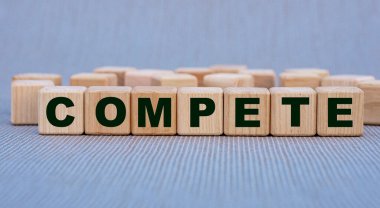 COMPETE - güzel gri bir arka planda tahta küplerle ilgili bir söz. İş konsepti