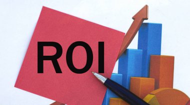 ROI (Yatırım Dönüşü) - grafiğin arka planında bir kalem olan kırmızı kağıt üzerinde kelime. İş ve finans kavramı