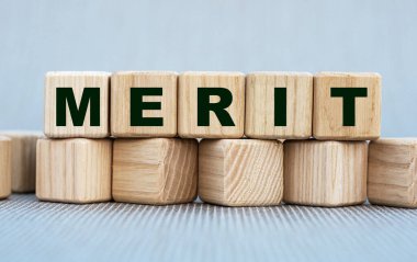 Merit, güzel gri bir arka planda tahta küplerle ilgili bir söz. İş konsepti