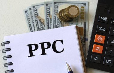 PPC (Click başına ödeme) - bir dizüstü bilgisayardaki sözcükler hesaplama ve banknotların arka planına karşıdır. İş ve finans kavramı.