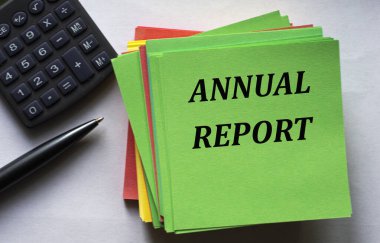 ANNUAL REPORT - bir hesap makinesi ve bir kalemin arka planına karşı yeşil bir not kağıdı üzerinde metin. İş ve finans kavramı.