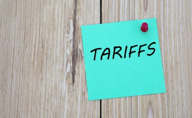TARIFFS - notlar için yeşil bir sayfaya yazılmış kelime, ki bu da tahta bir tahtaya tutturulmuştur. İş konsepti
