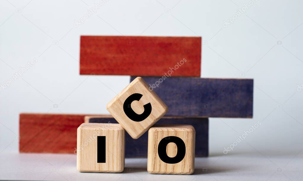 ICO (Initial Coin Offering) - acronym on wooden cubes on a background of colored block on a light background. Technology concept