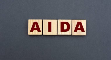 Gri arka planda tahta küplerin kısaltması AIDA. İş konsepti