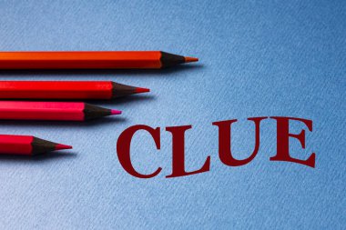 KLUE - yanında kırmızı kalemler olan gri kağıt üzerinde kelime. Finans ve eğitim kavramı