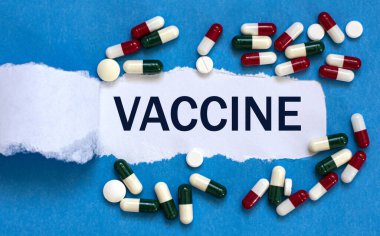 VACCINE kelimesi yırtık kağıtların üzerine yazılır. Tıp konsepti.