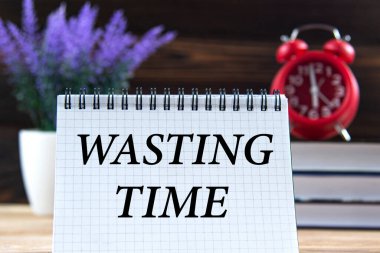 Zamanı boşa harcamak - kitapların, çalar saatin ve lavantanın arka planına karşı dizüstü bilgisayardaki kelimeler. İş konsepti