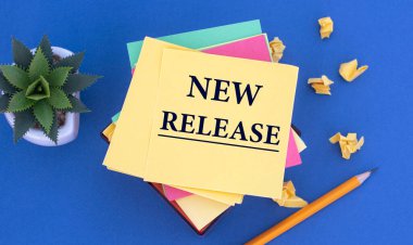 YENİ RELEASE - mavi arka planda sarı bir not kağıdındaki kelimeler. Kalem, kaktüs, buruşmuş kağıt parçaları. İş konsepti
