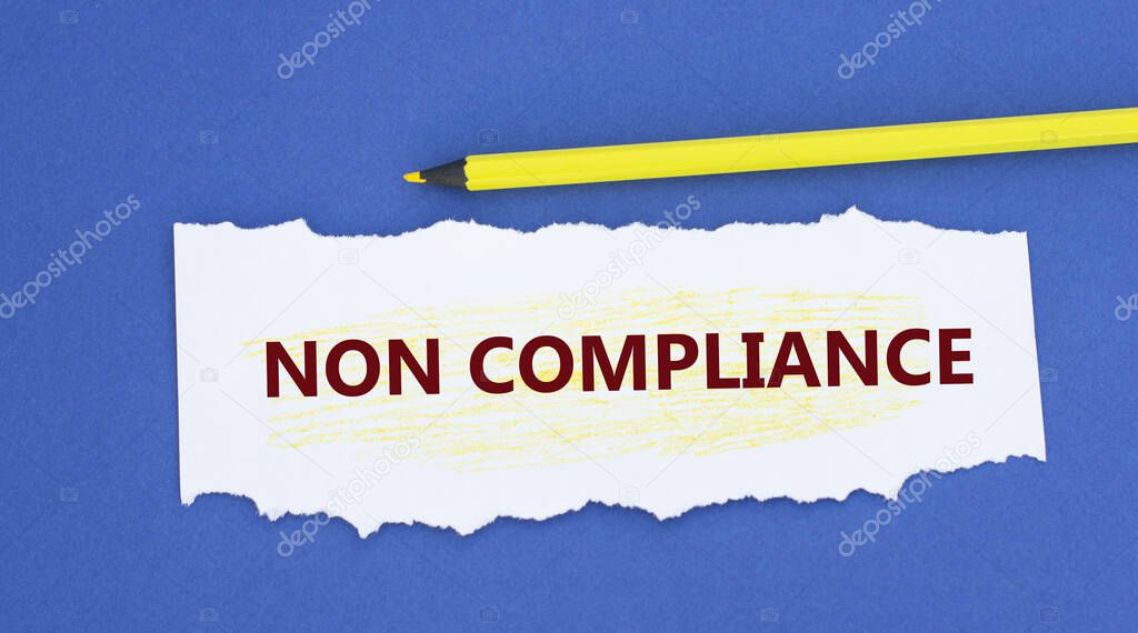 NON COMPLIANCE - words on a torn white paper on a blue background. Info concept