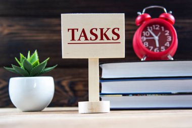 TASKS - tahta bir tahta üzerinde bir kelime kitapların arka planına karşı, bir çalar saat, bir kaktüs. Bilgi kavramı