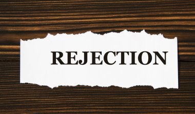 REJECTION - tahta bir arka planda beyaz yırtık bir kağıt parçası üzerinde kelime. Bilgi kavramı