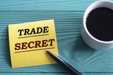 TRAD GİZLİ - Yeşil ahşap zemin üzerinde sarı bir kağıt üzerinde bir fincan kahve ve bir kalem ile kelimeler. Bilgi kavramı