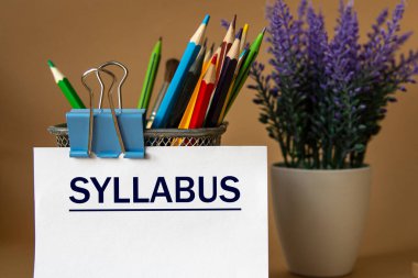 SYLLABUS - word on a white sheet against the background of pencils and a bouquet of lavender. Education concept