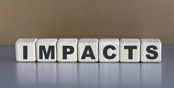 IMPACTS - word on wooden cubes on a beautiful gray background. Business concept