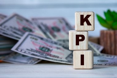 KPI (Anahtar Performans Göstergesi) - bir kaktüs ve banknotların arka planında tahta küplerin kısaltması. İş konsepti
