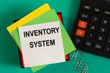 INVENTORY SİSTEM - nota kağıdındaki kelimeler bir hesap makinesi ve ataçların arka planına karşı. İş konsepti