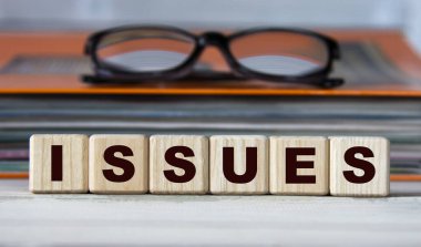 ISSuES - evrak ve gözlüklü bir klasörün arka planındaki tahta küplerle ilgili kelime