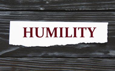 HUMILITY - siyah ahşap bir arka planda yırtık bir kağıt parçası üzerinde kelime. Bilgi kavramı