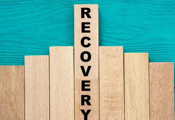 RECOVERY - word on wooden bars on a green background. Info concept