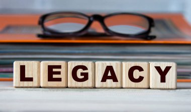 LEGACY - evrak ve gözlüklü bir klasörün arka planındaki tahta küplerle ilgili kelime