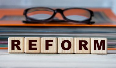 REForM - evrak ve gözlüklü bir klasörün arka planındaki tahta küplerle ilgili bir söz. İş konsepti