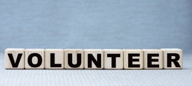 konsept kelime VOLUNTEER üzerinde ahşap küpleri güzel gri bir arka plan.