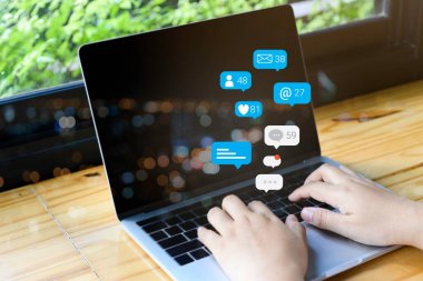 Bilgisayar dizüstü bilgisayarında sosyal medya pazarlama kavramı kullanan kişi, bildirim simgeleri kullanarak, sohbet, mesaj ve dizüstü bilgisayarın üzerinde yorum yapar.