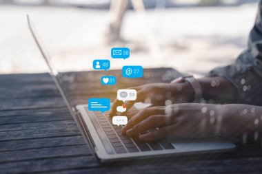 Bilgisayar dizüstü bilgisayarında sosyal medya pazarlama kavramı kullanan kişi, bildirim simgeleri kullanarak, sohbet, mesaj ve dizüstü bilgisayarın üzerinde yorum yapar.