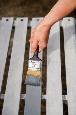 Boya fırçası kullanarak beyaz kereste tahtalarını gri boyayla boyama işlemi. 