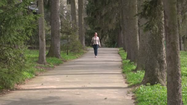 公園を歩いている若い女性は — ストック動画