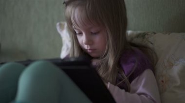 Kanepede oturan ve tablet ile oynarken küçük şirin kız